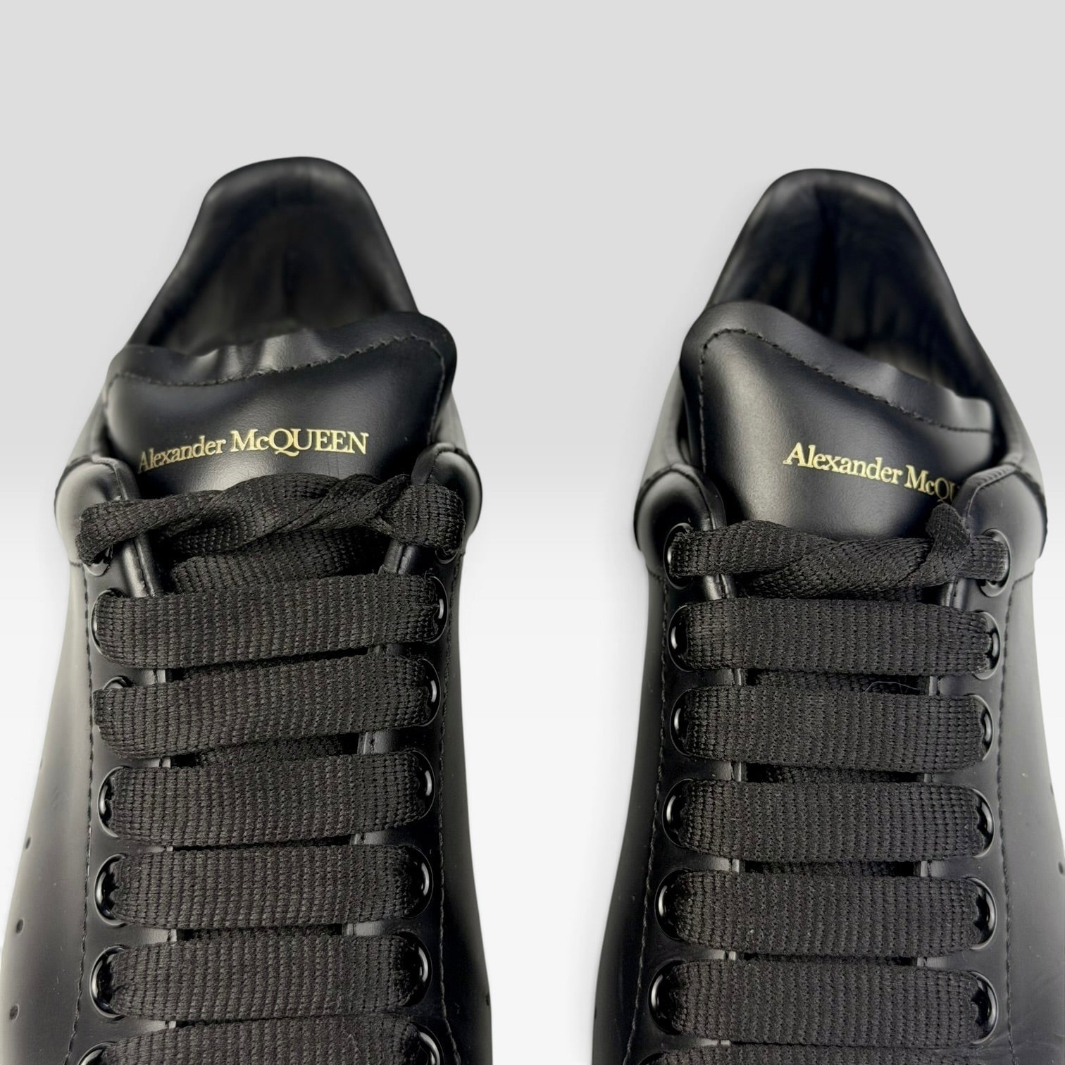 V STEALS Alexander McQueen black leather oversized sneakers with gold logo detail on the tongue