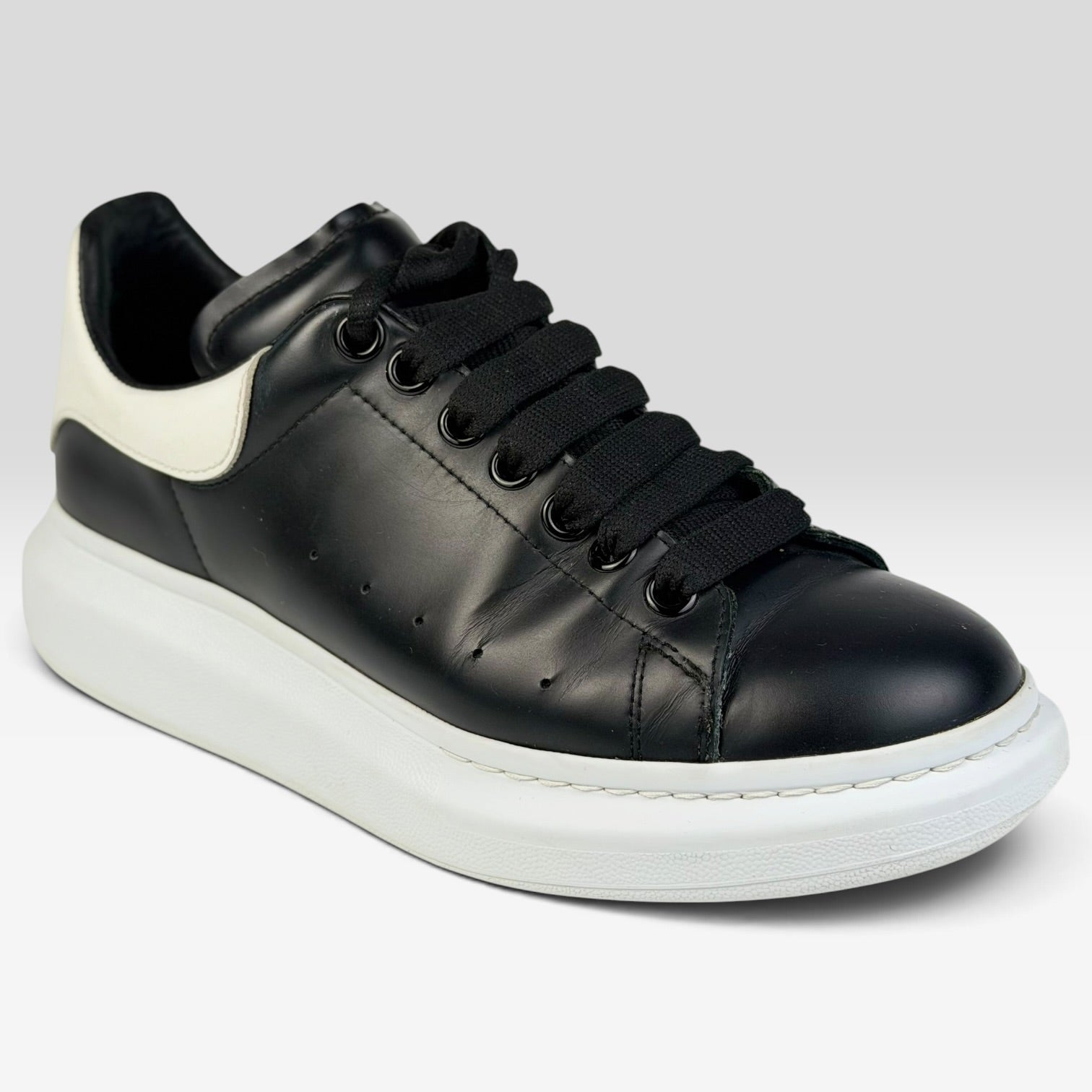 V STEALS Alexander McQueen black leather oversized sneakers with a thick white rubber sole and rounded toe.