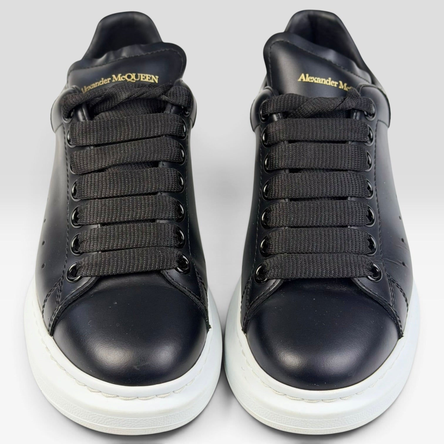 V STEALS Alexander McQueen black leather oversized sneakers with thick white rubber soles and gold logo branding