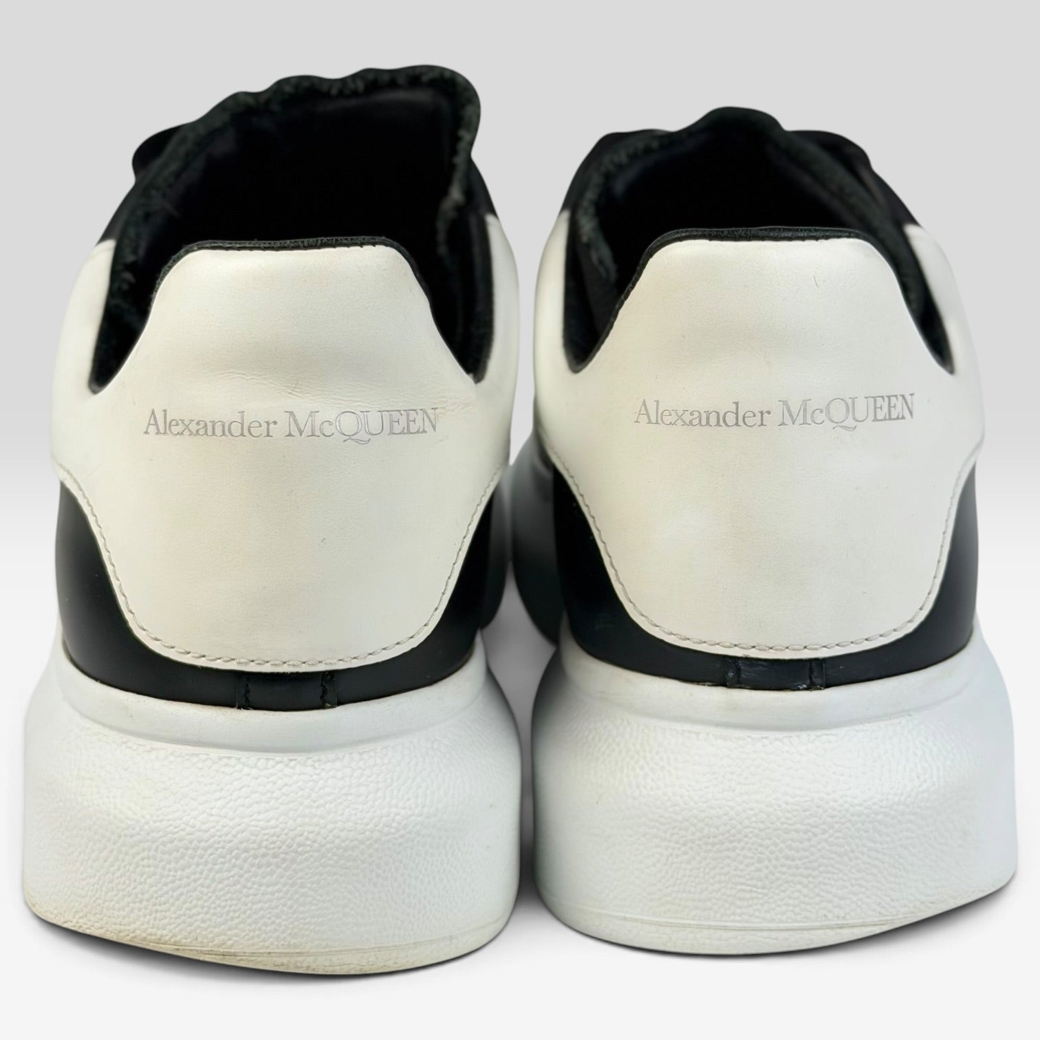 V STEALS Alexander McQueen black and white leather oversized sneakers, rear view showing embossed logo on heel tabs