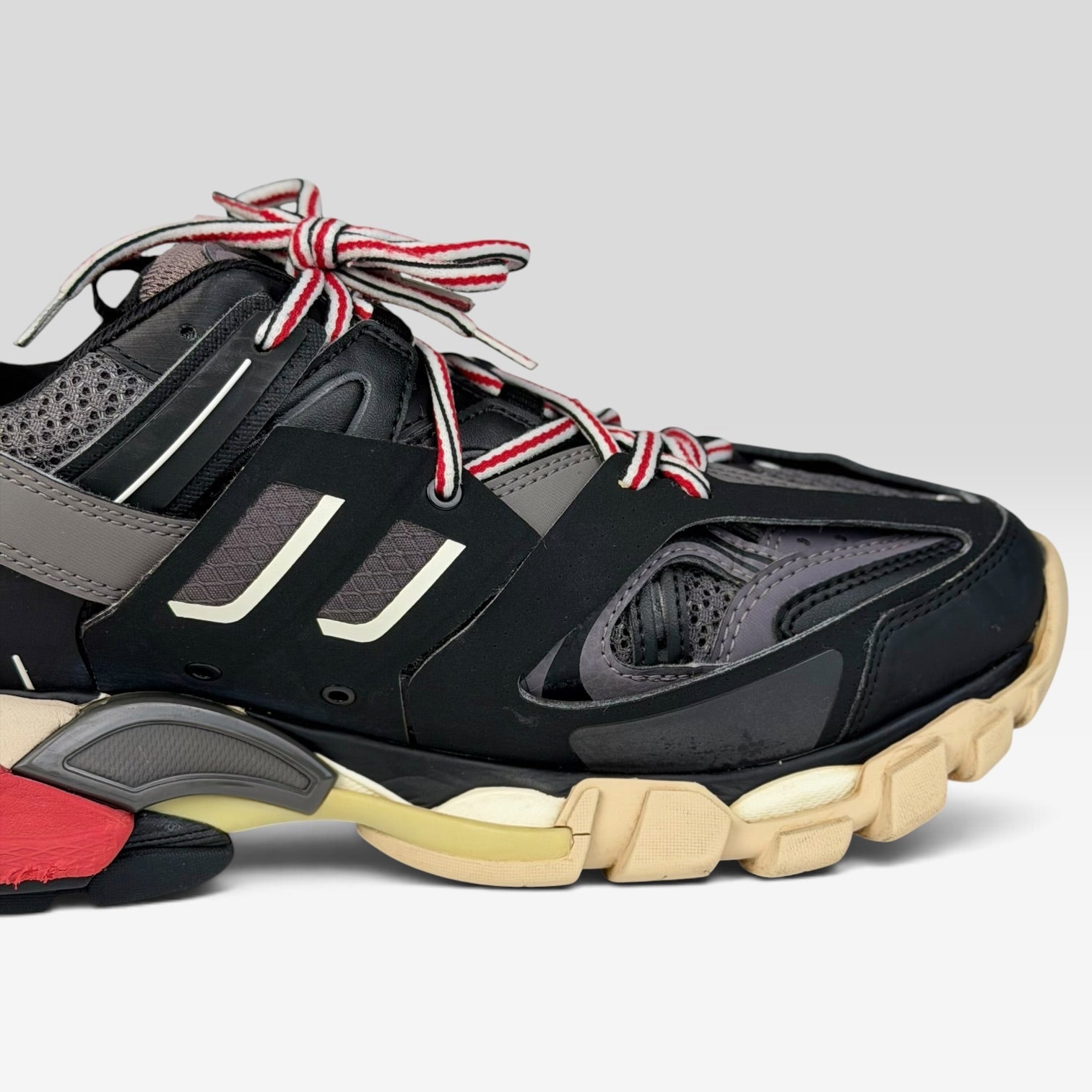 V STEALS Balenciaga Track Bred sneakers featuring black mesh, red and black striped laces, and a chunky lugged sole.